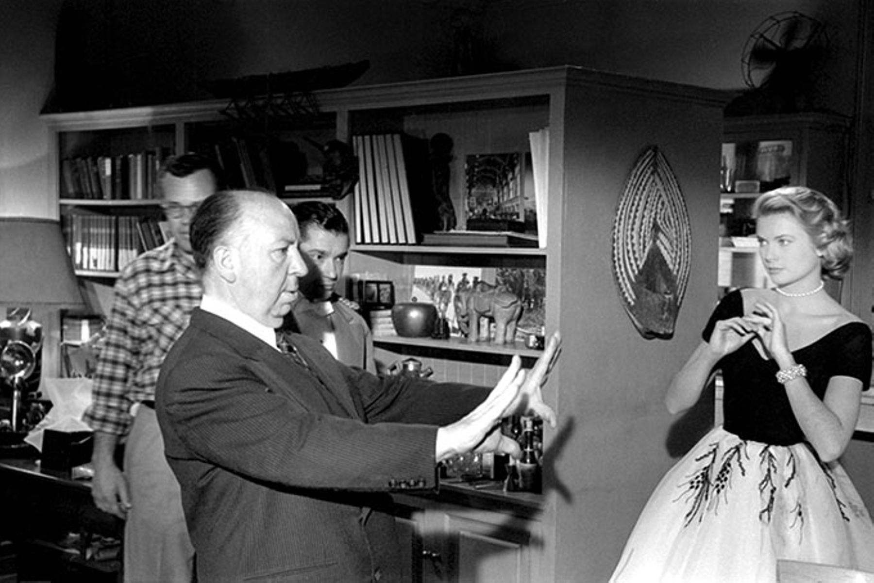 Alfred Hitchcock plans a shot with his crew and actress Grace Kelly on the set of Rear Window.