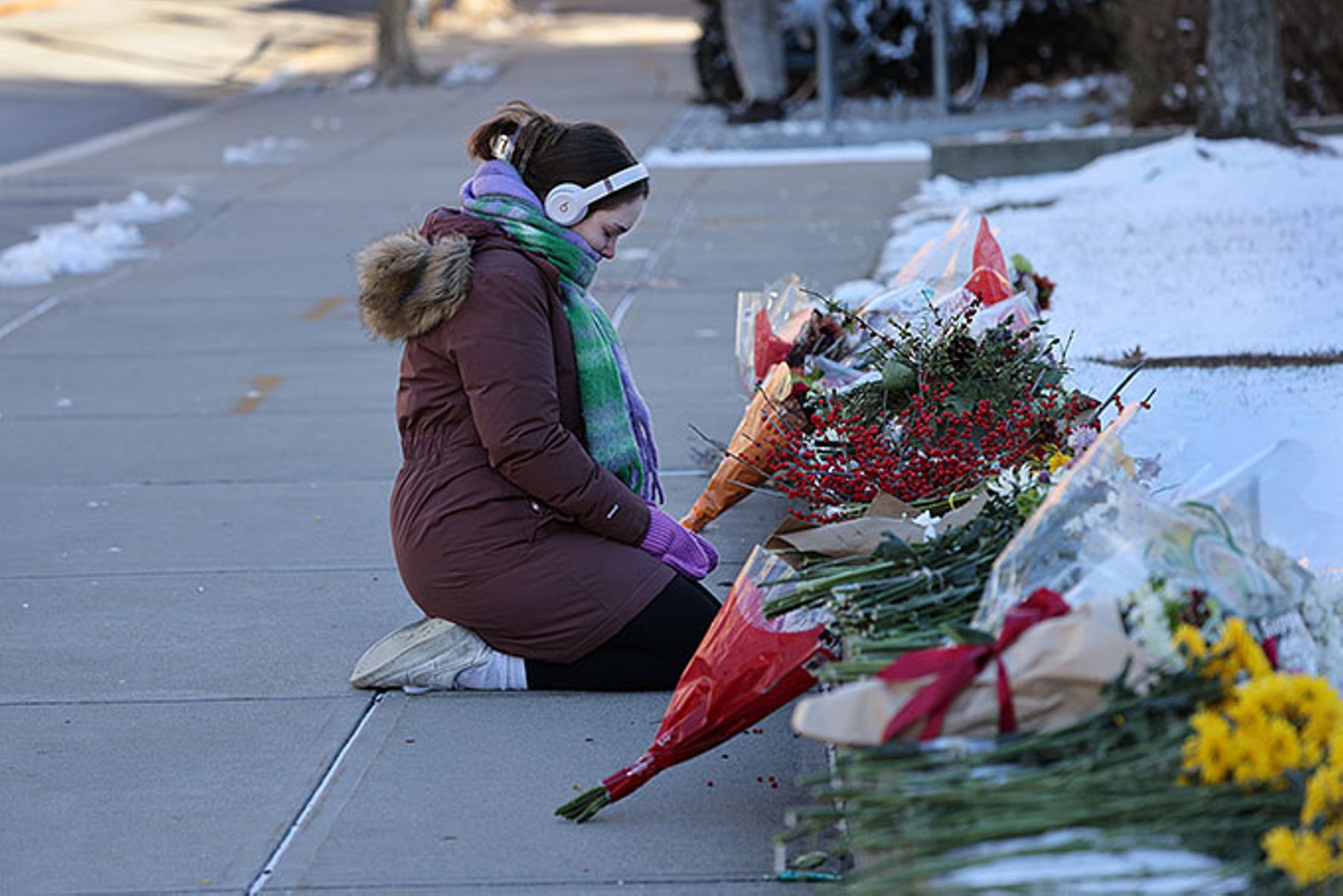 Brown University student kneels in front of a memorial at the Barus and Holley School.