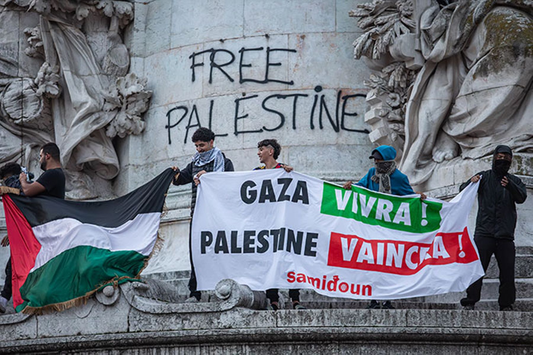 Palestinian flag and demonstrators with a “Gaza vivra ! Palestine vaincra, Samidoun” banner at a Paris protest, Oct. 12, 2023.