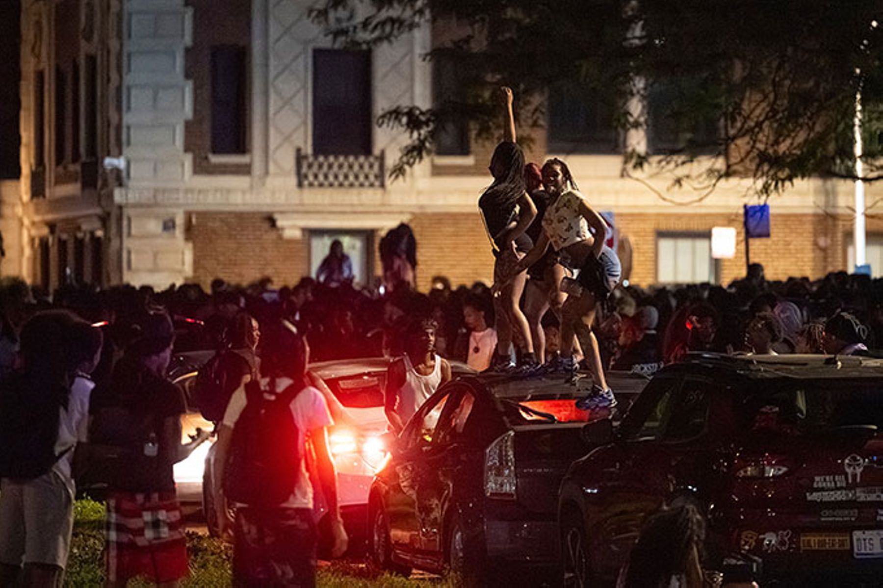 Young women dance on top of a car near the Griffin Museum of Science and Industry in the Hyde Park neighborhood as Chicago police officers attempt to disperse hundreds of other young people, Monday, May 25, 2026.