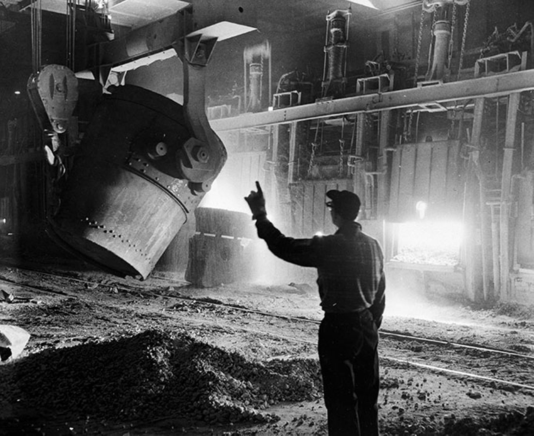 1952-Gary, IN. Gary Steel Works, worker directs the addition of molten iron into the open hearth furnace. 