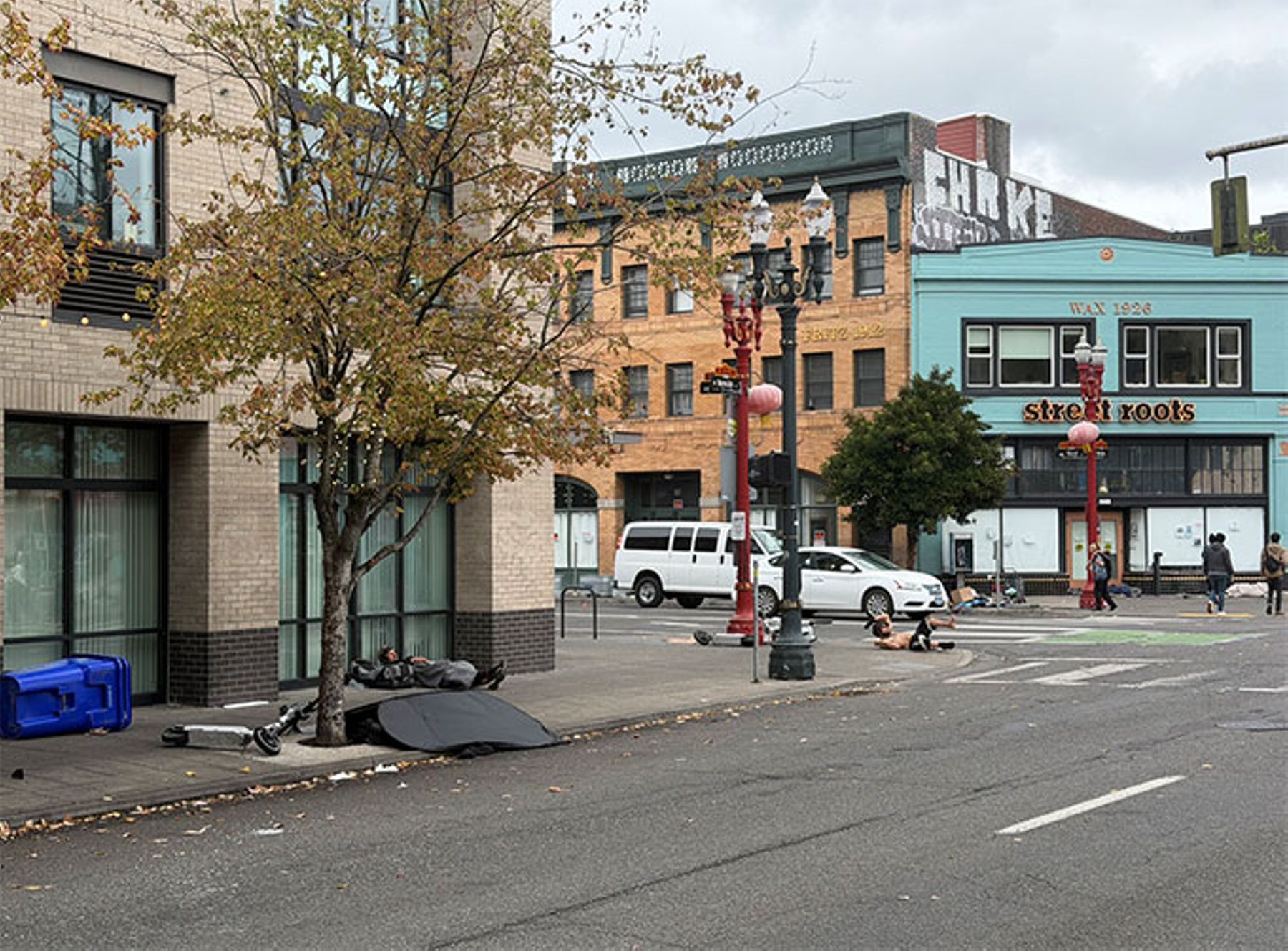 In Portland, a homeless man lies on the sidewalk, bare-chested and likely under the influence of drugs.